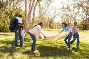 Family puts down blanket for outdoor picnic