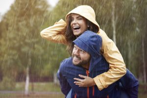 Happy couple wearing waterproof jackets in rain