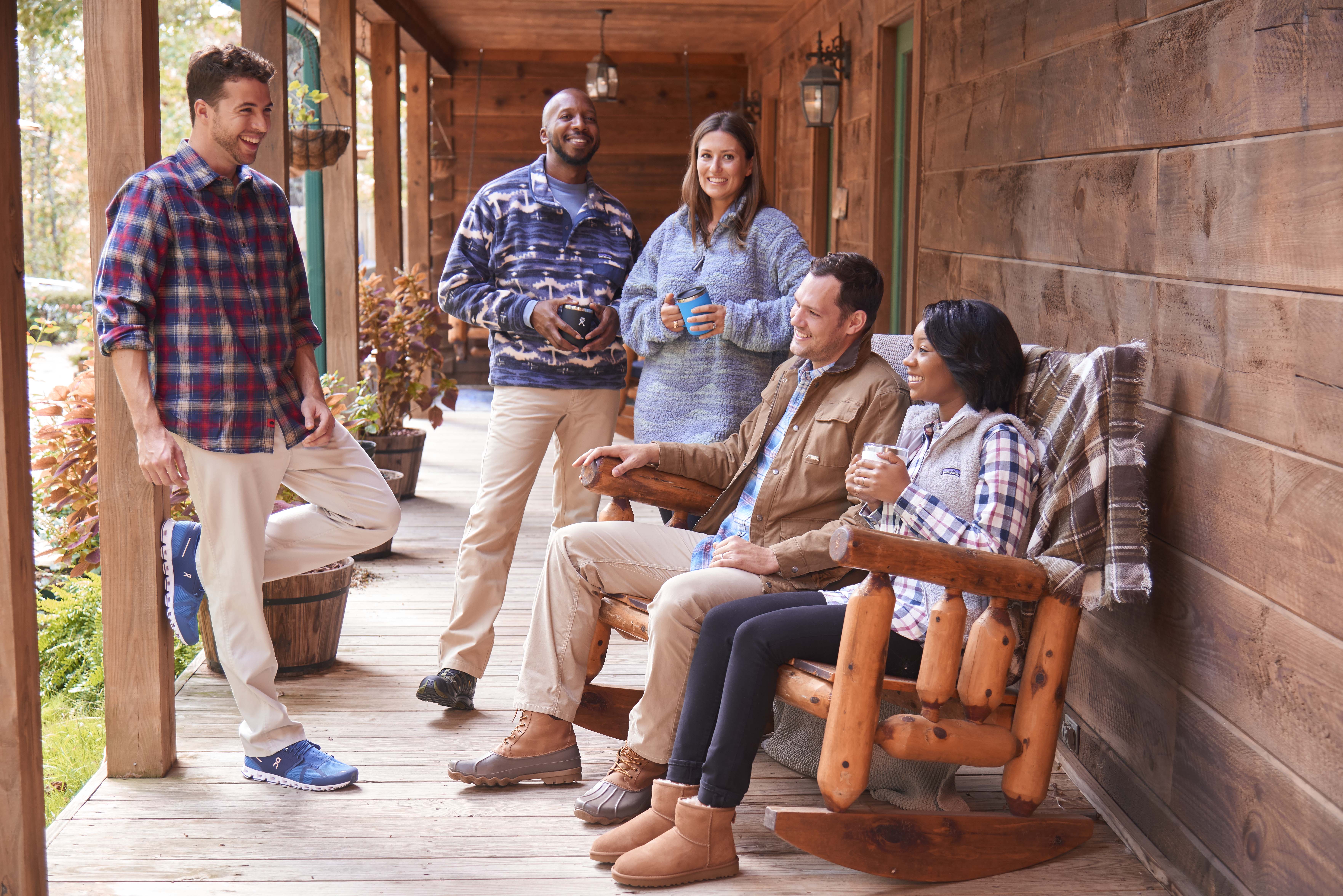 Friends relax on porch of cozy cabin.
